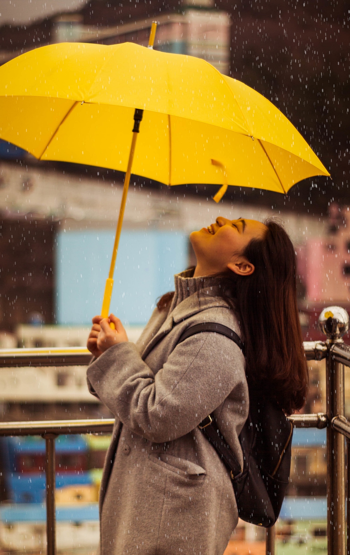 woman with yellow umbrella smiling in the rain