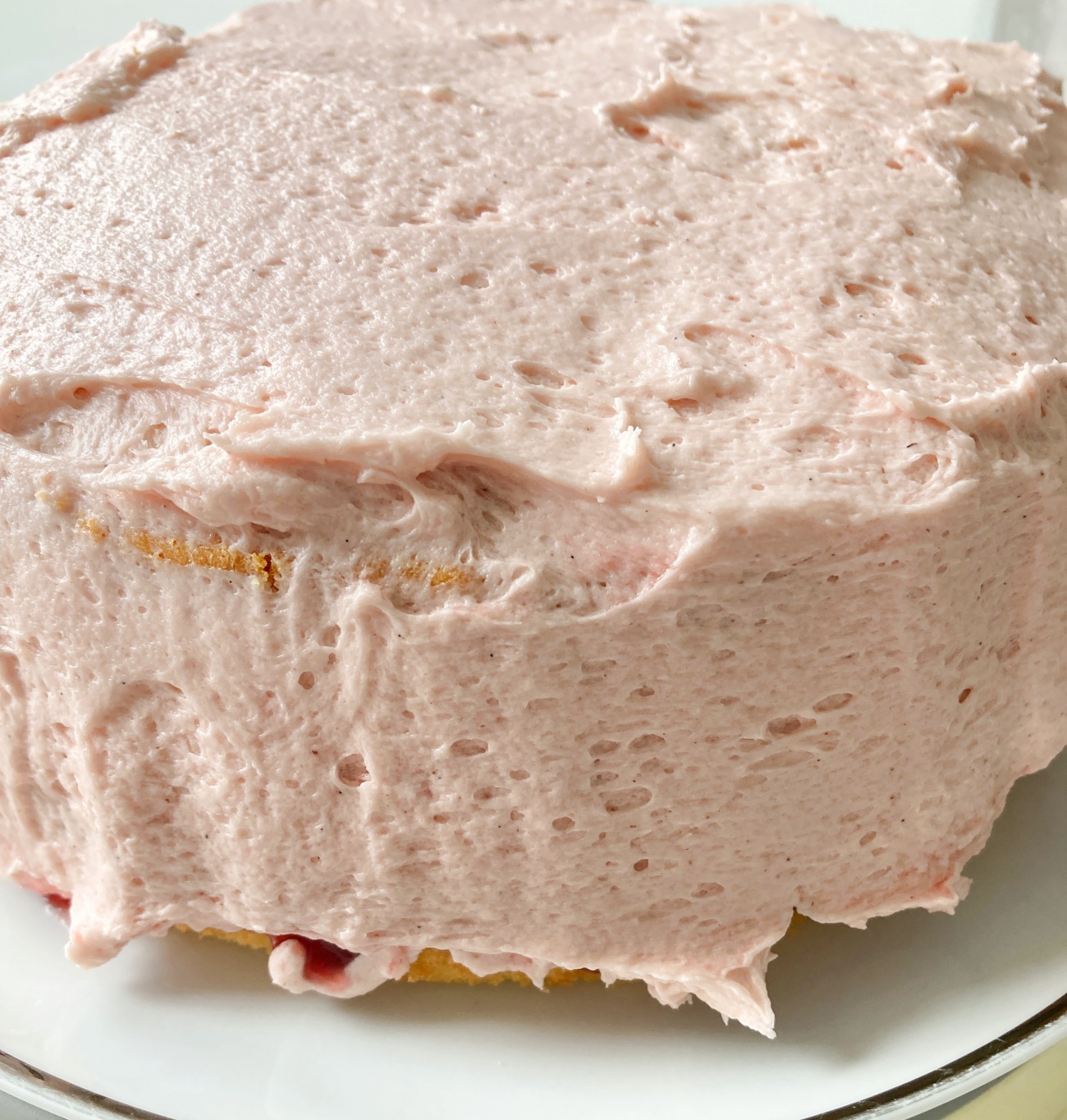 Add second cake on top and cover entire cake in a layer of raspberry frosting. Use a frosting comb to decorate or pipe on rosettes on top using plain or raspberry frosting.