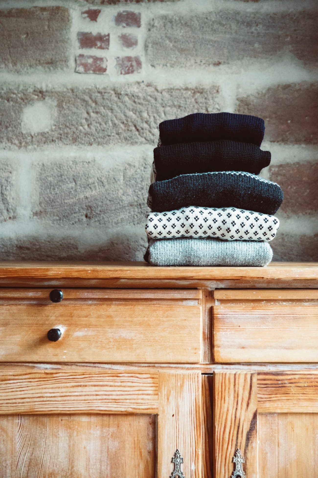 dresser with sweaters stacked on top