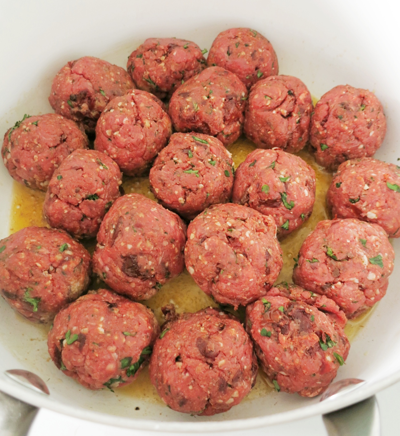 Chop up tomatoes. Combine beef, egg, breadcrumbs, parsley, tomatoes, parmesan, garlic, tomato paste, oregano, and basil. Roll into 18 meatballs.