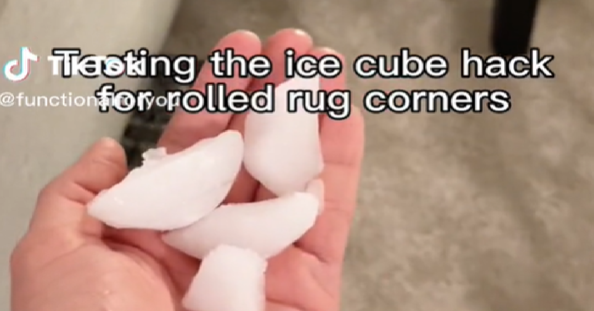 Add cup of ice to curled up rug corner, place cup to weigh down