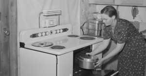 1940s housewife pulling a covered pan out of the oven