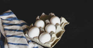 half carton of eggs next to a blue and white dish towel