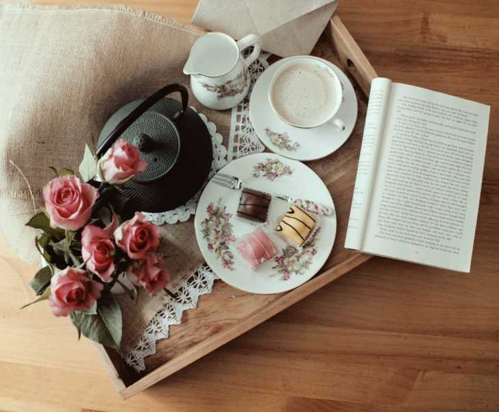 tray with teacup, chocolates, book, and flowers