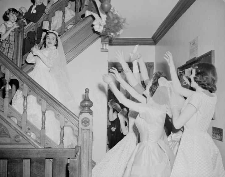 1950s bride throwing her bouquet on a set of stairs