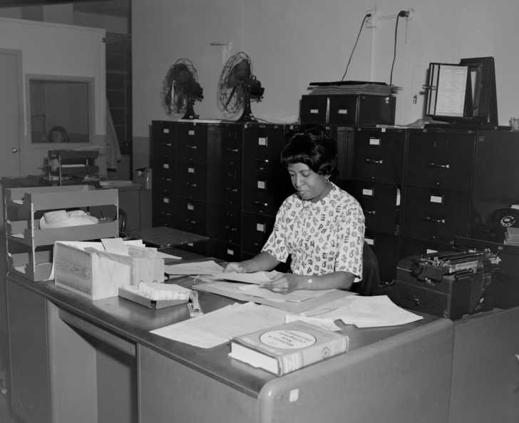 woman working at a desk in an office in the 1960s