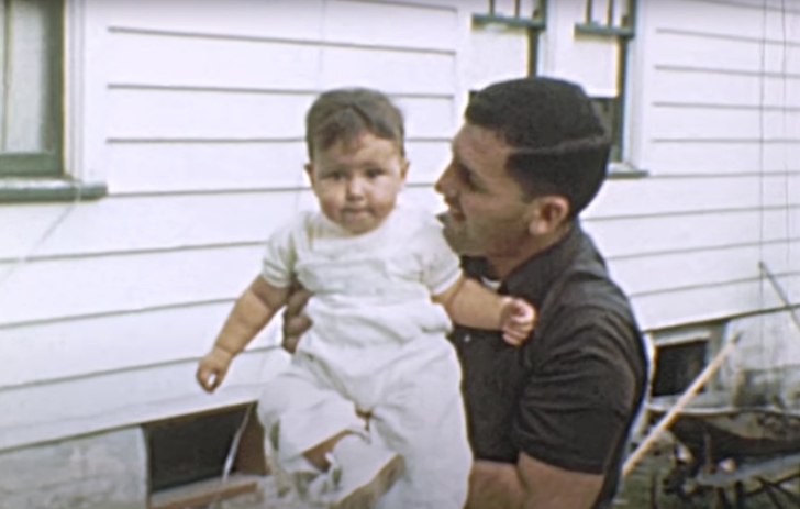 father holding up his toddler son, 1950s