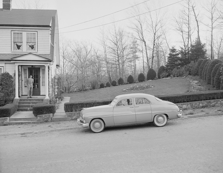 1950s house and car with man standing on porch