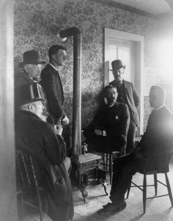 men sitting around a small stove late 1800s