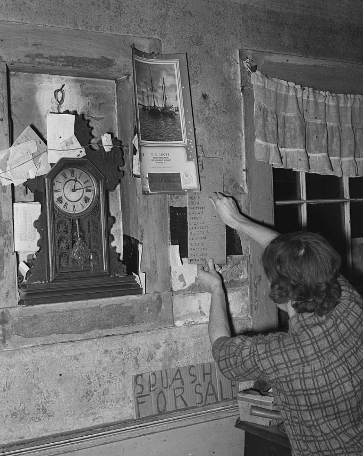 woman tacking a grocery list to the wall, 1930s