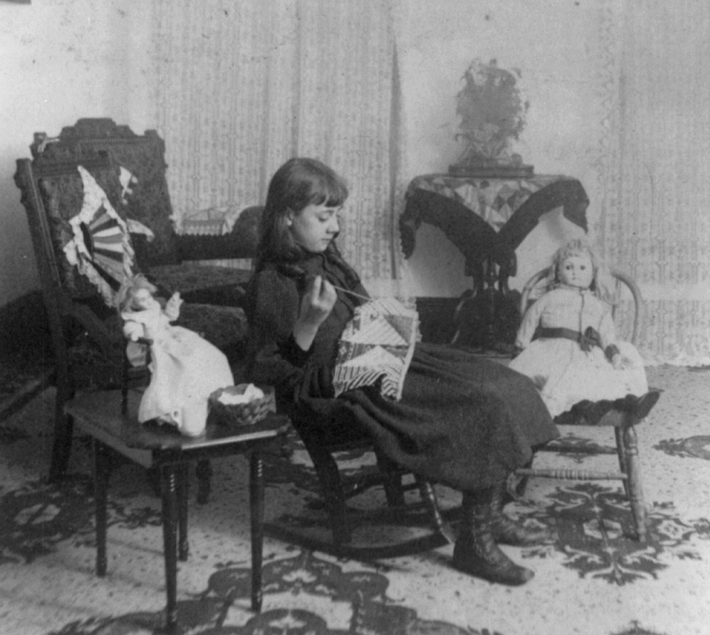 1890s girl sewing near her dolls