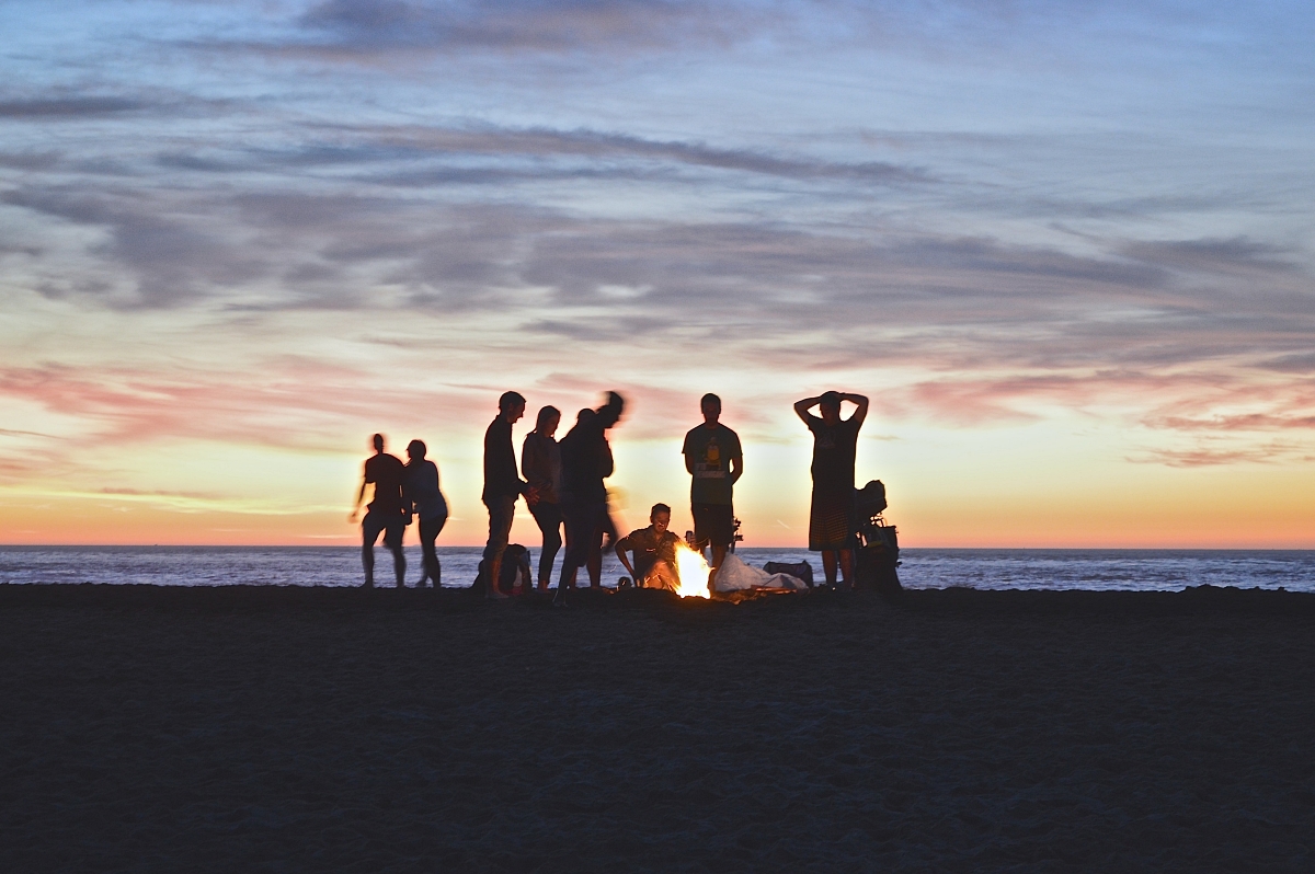 young people at a beach campfire at sunset