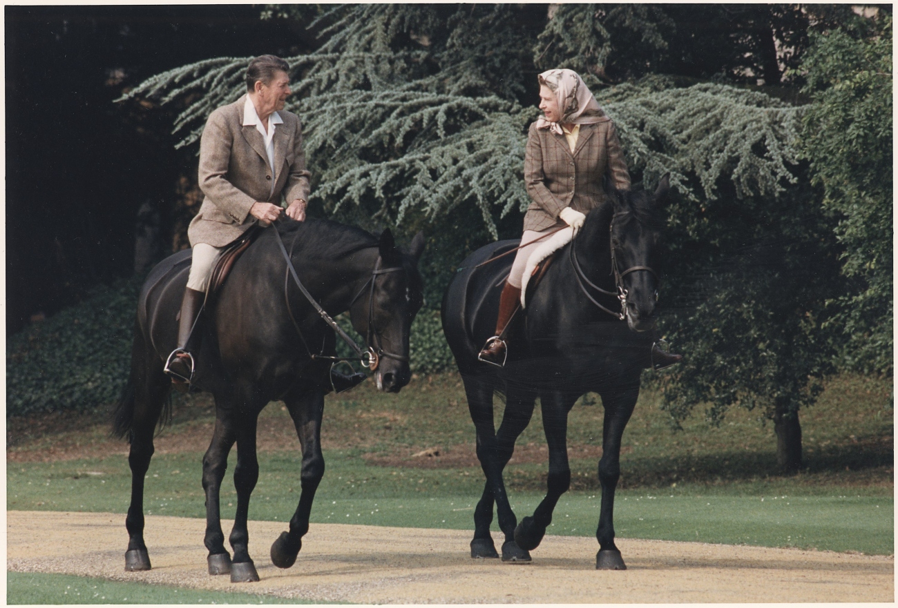 QEII wearing head scarf and riding horse with Reagan
