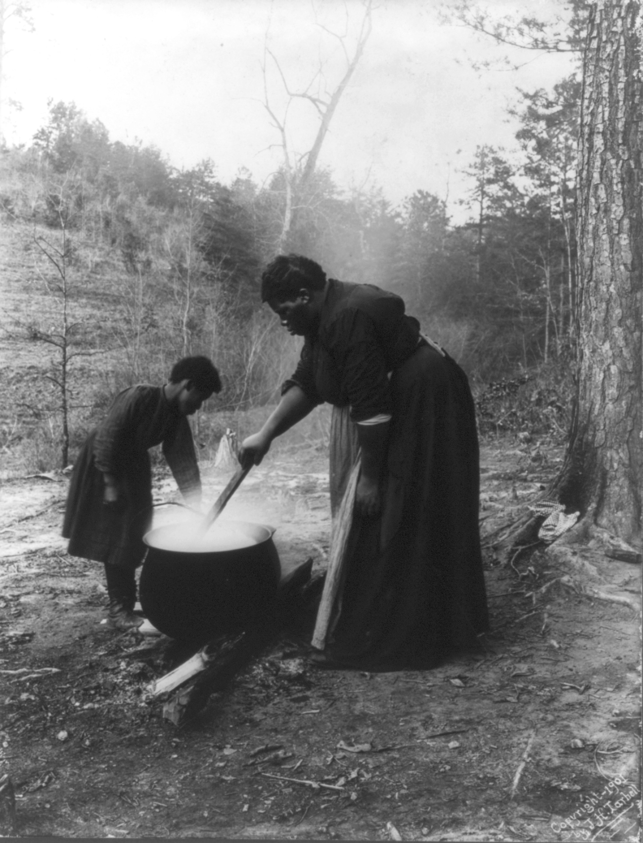 washing clothing in cauldron over open fire