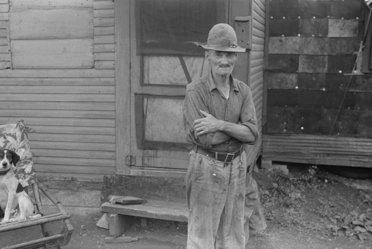 former farmer in front of shack