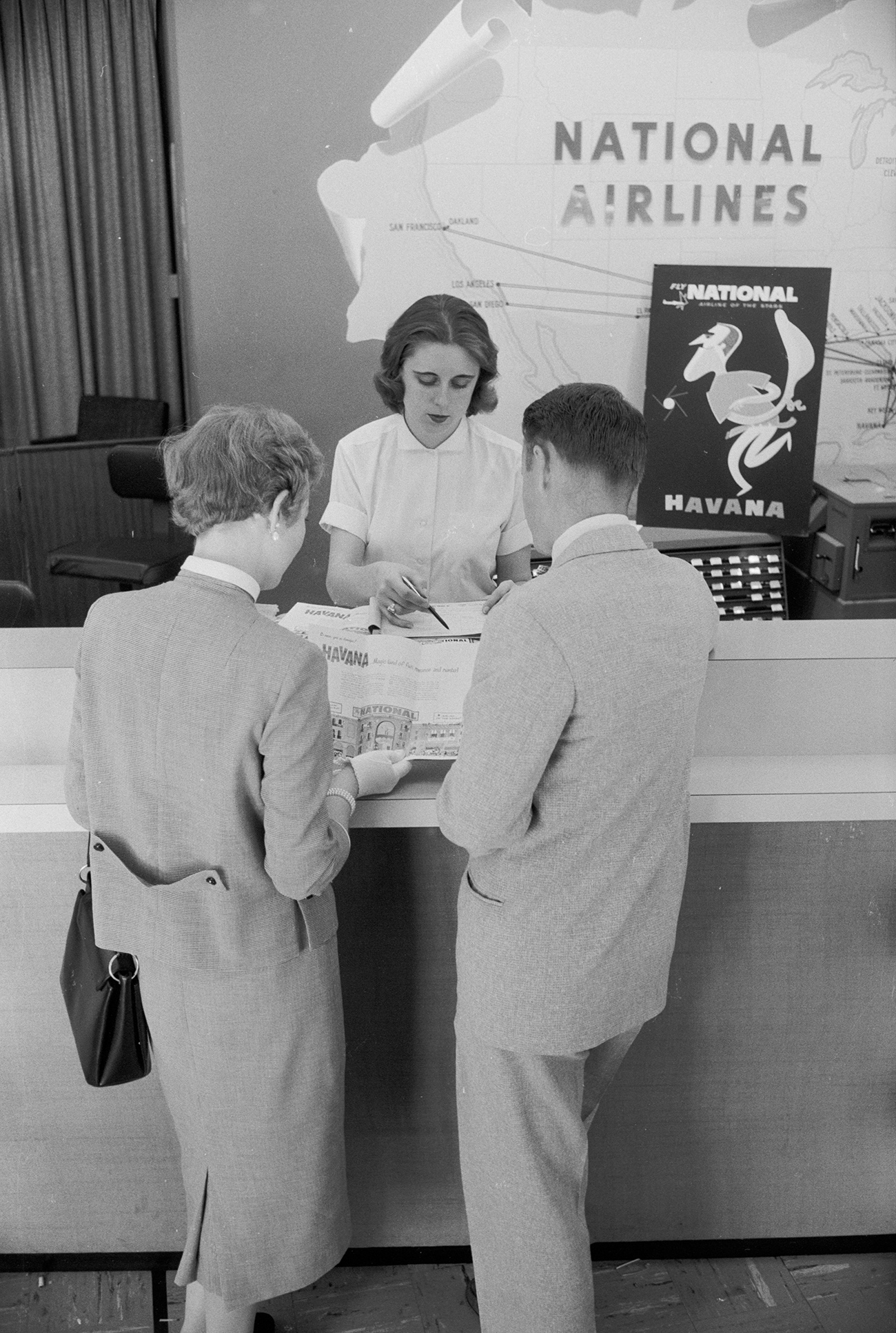 couple looking at vacation packages in 1957