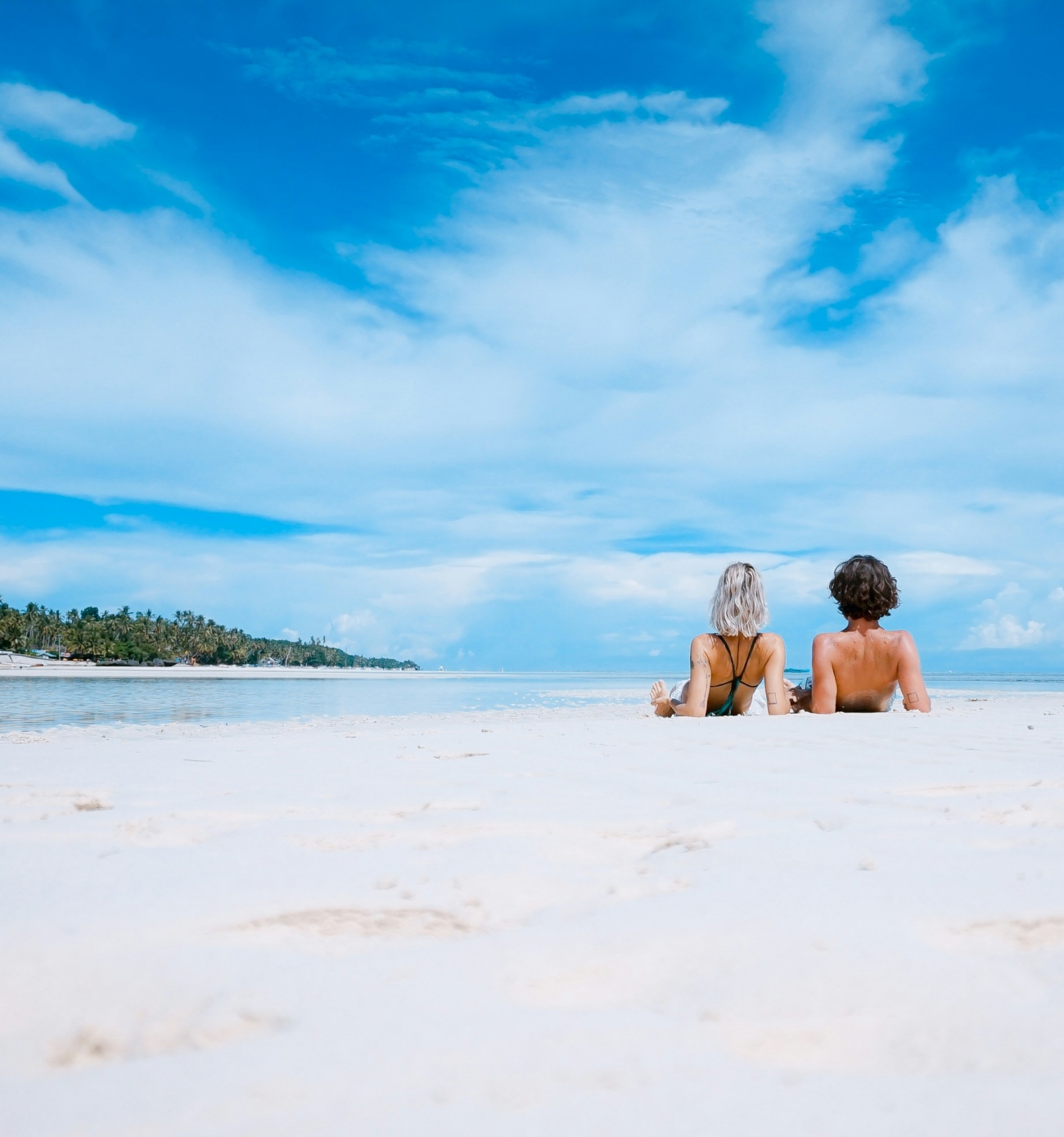 Two People Lying Down on a Sandy Beach