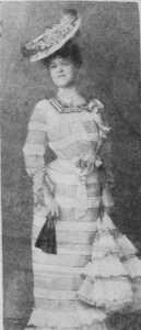 A woman in a vintage striped dress and wide-brimmed hat poses gracefully.