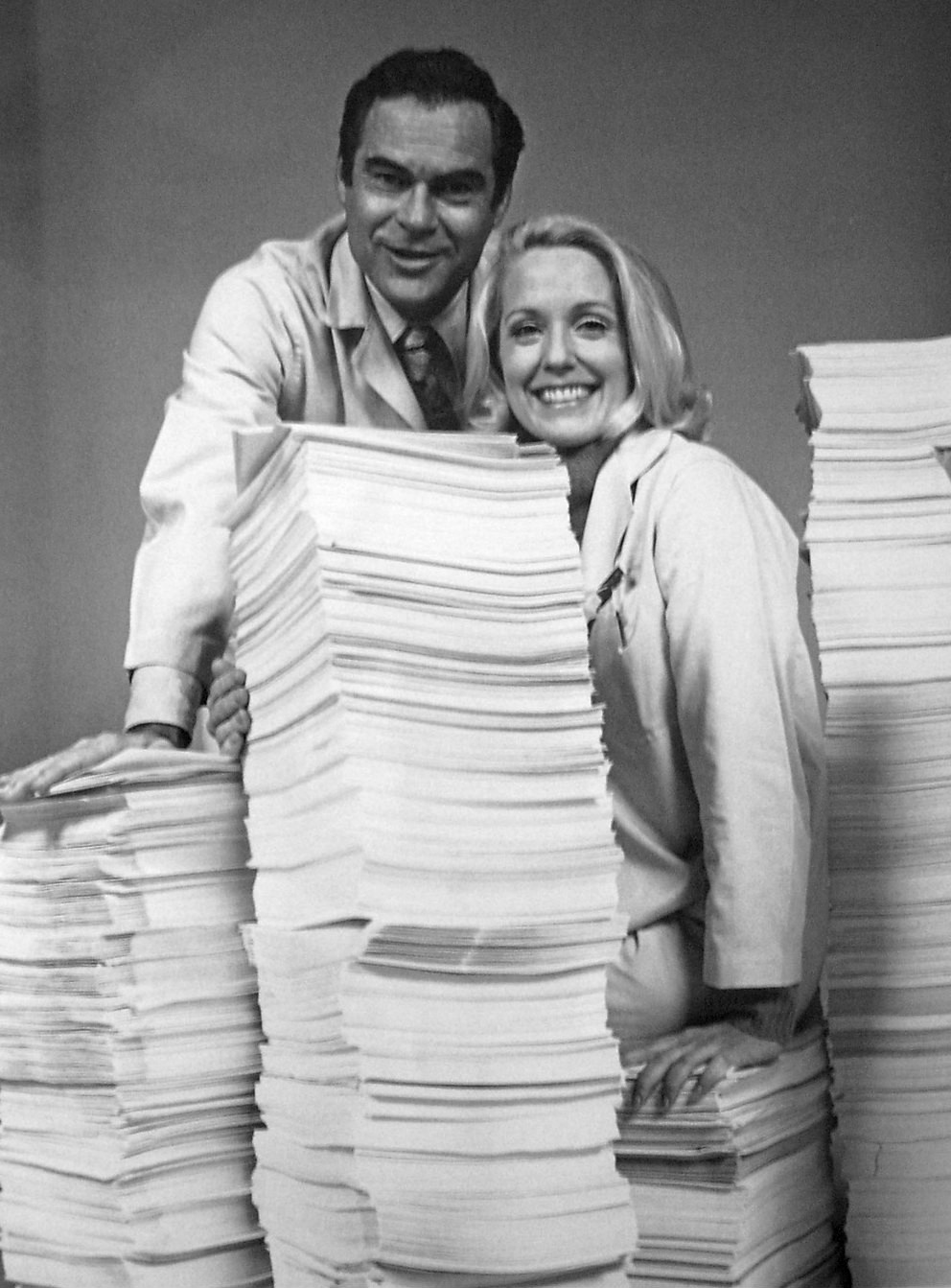 Photo of James Pritchett (Matt Powers) and Elizabeth Hubbard (Althea Davis) from the daytime drama, The Doctors. They pose with 10 years worth of scripts to celebrate the show's 10th anniversary.