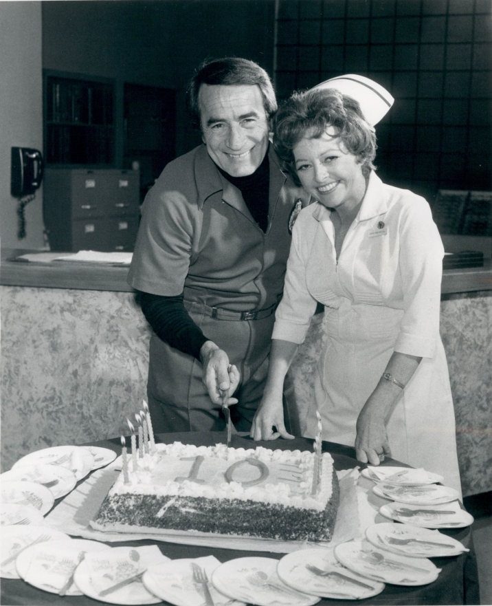 Publicity photo for the 10th Anniversary of General Hospital. The pictured cast are John Beradino (as Dr. Steve Hardy) and Emily McLaughlin (as Jessie Brewer).