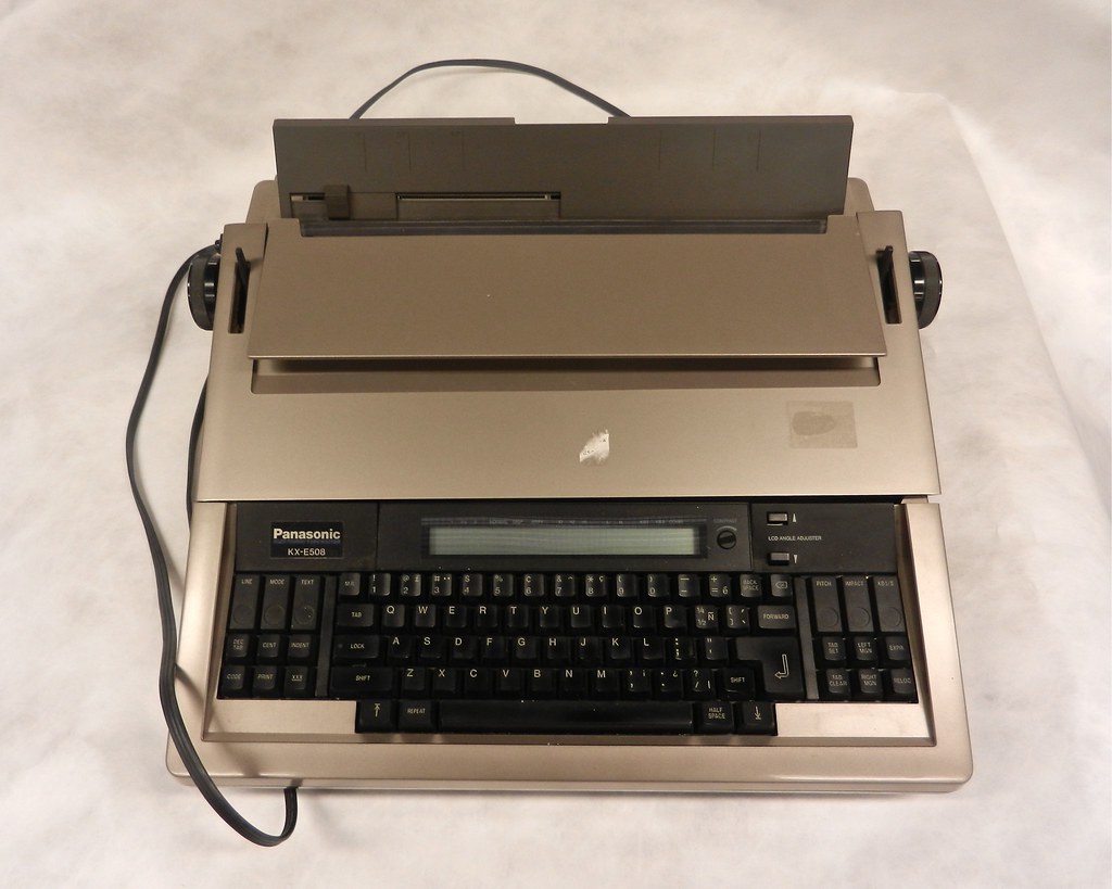 Beige Panasonic KX‑E508 electric typewriter with LCD and black keyboard, top-down on white; text reads 'Panasonic KX‑E508'.