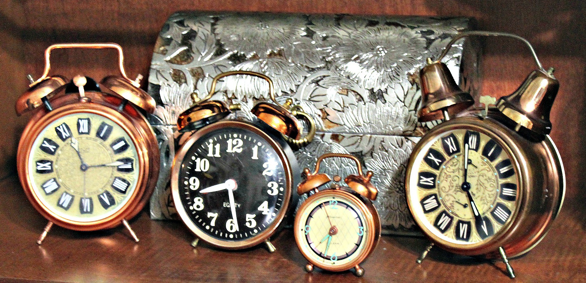 A diverse assortment of clocks arranged on a table, each with unique designs and colors, ticking in harmony.