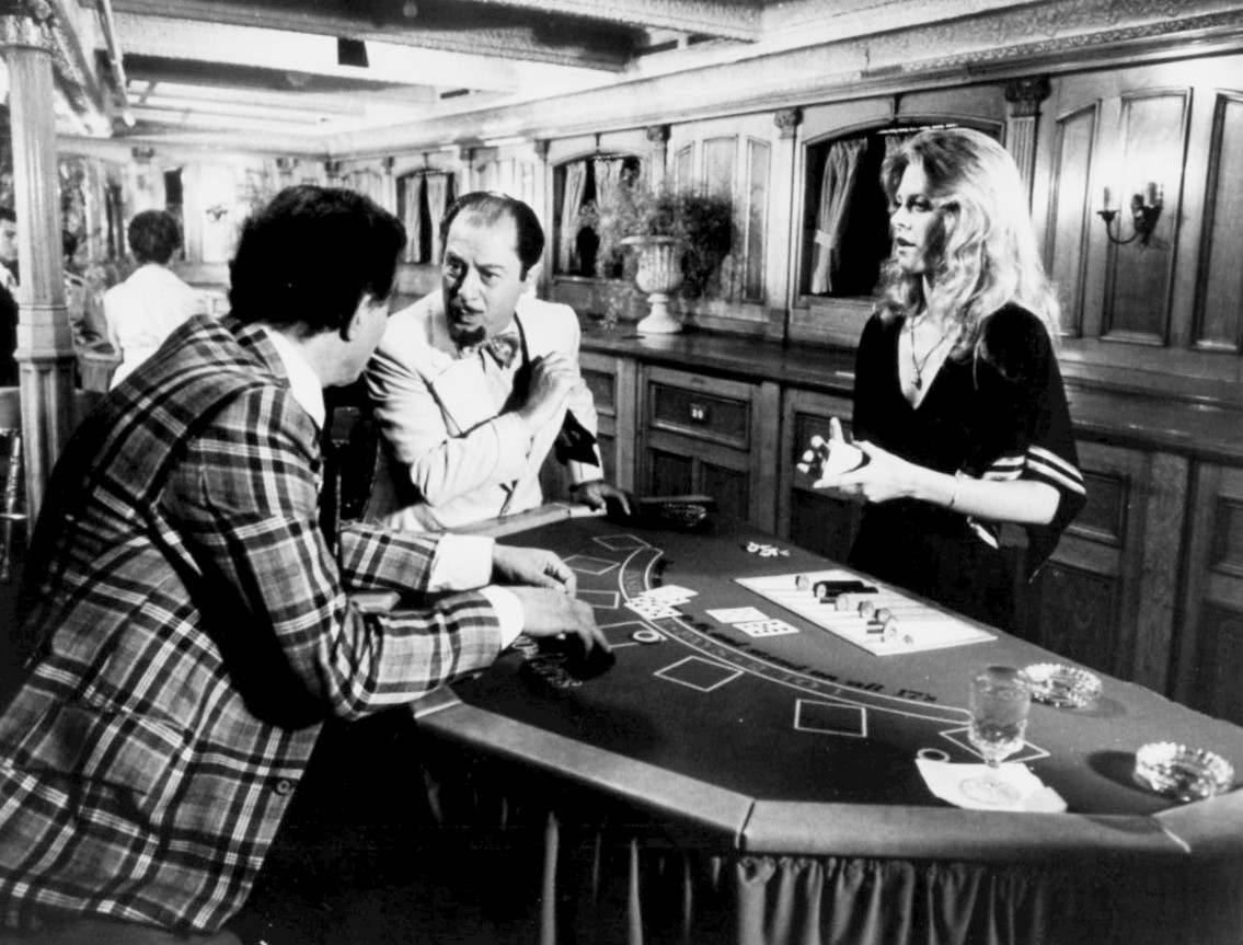 Two men and a Lindsay Wagner (as Jaime Sommers) play cards in a vintage casino setting in a scene from The Bionic Woman.
